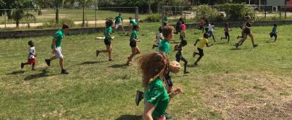 Local school children participate in a Physical Education class run by volunteers in Belize. A group of volunteers in Belize run a sports coaching class at a local school.
